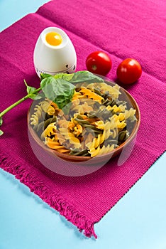 Uncooked Italian Fusilli Pasta with kitchen timer and basil