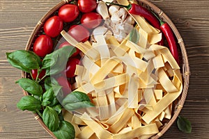 Uncooked Italian noodles with garlic, basil, tomatoes cherry and