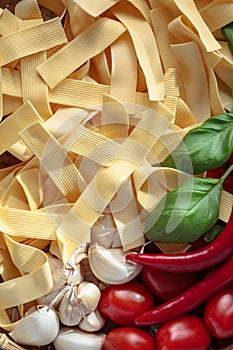 Uncooked Italian noodles with garlic, basil, tomatoes cherry and