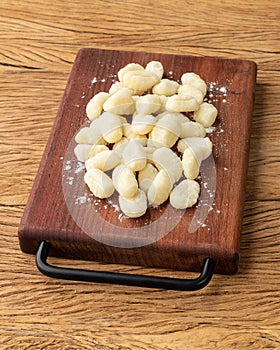 Uncooked italian pasta gnocchi on a board over wooden table
