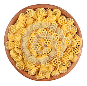 Uncooked italian pasta rotelle in a wooden bowl on a white