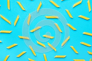 Uncooked Italian Penne Pasta Scattered on Blue Background. Food Pattern. Bright Vibrant Yellow Color.