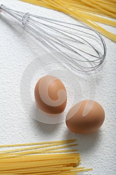 Uncooked macaroni, whisk and eggs