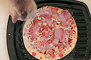 Uncooked meat pizza on a black tray