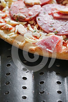 Uncooked meat pizza on a black tray