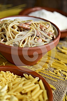 Uncooked pasta, spaghetti alla carbonara and grated cheese