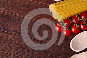 Uncooked pasta, tomatoes on wooden background, top view, close-up, selective focus