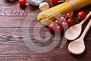 Uncooked pasta, tomatoes on wooden background, top view, close-up, selective focus