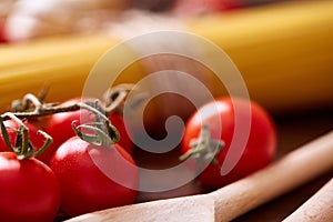 Uncooked pasta, tomatoes on wooden background, top view, close-up, selective focus