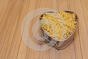 Uncooked pasta on wooden background - heart shaped - Copy space
