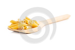 Uncooked penne pasta. Dried italian pasta in wooden spoon