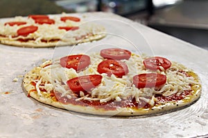 Uncooked Pizza being prepared on a stainless steel table.