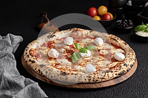 an uncooked pizza on wooden board with tomatoes and basil