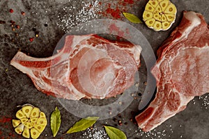 Uncooked pork chops rib with spices on gray background