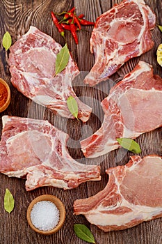 Uncooked pork chops rib with spices on wooden background