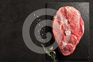 Uncooked Pork Ham steak on a stone kitchen cutting board.