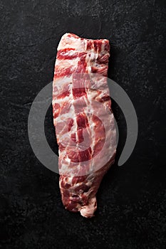 Uncooked pork ribs on dark textured background