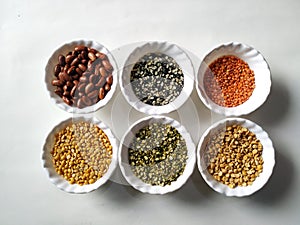 Uncooked pulses,grains and seeds in White bowls over ston background. selective focus