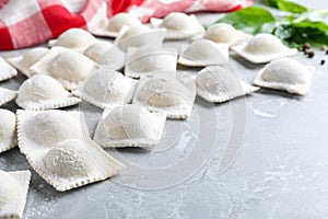 Uncooked ravioli on grey marble table, closeup. Space for text