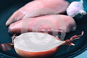 Uncooked Raw Chicken Breasts, Fillets, Chopped Half Onion, Whole Garlic Bulb on a Frying Pan. Healthy Organic Food, Poultry Meat