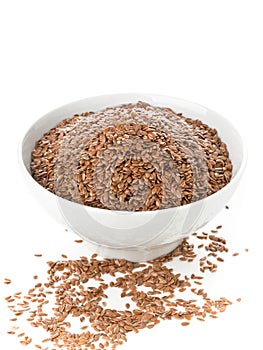 Uncooked, raw linseed or flax seed in white bowl over white back