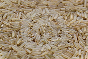 Uncooked raw long brown rice grains background, top view