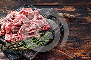 Uncooked Raw meat diced for stew on a butcher board. Dark Wooden background. Top View. Copy space