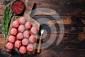 Uncooked Raw meatballs from ground beef and pork meat with rosemary. Dark Wooden background. Top view. Copy space