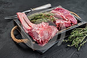Uncooked Raw Rack and lamb, mutton rib chops in a wooden tray. Black background. Top view