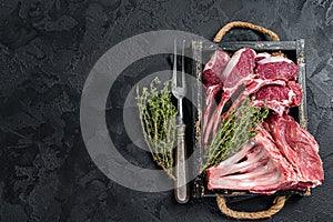 Uncooked Raw Rack and lamb, mutton rib chops in a wooden tray. Black background. Top view. Copy space