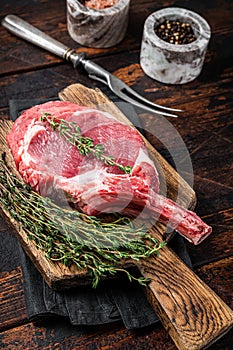 Uncooked Raw Rib eye or Tomahawk beef (veal) steak on butcher cutting board. Wooden background. Top view