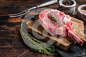 Uncooked Raw Rib eye or Tomahawk beef veal steak on butcher cutting board. Wooden background. Top view. Copy space