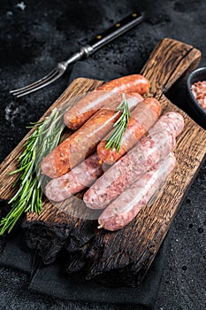 Uncooked Raw sausages Chorizo and Bratwurst with spices on wooden board. Black background. Top View