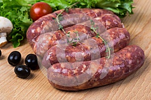 Uncooked raw sausages on wooden board