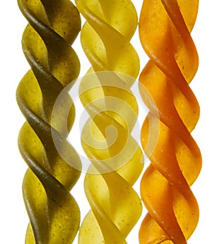 Uncooked raw tricolor macaroni pasta on white background. Macro food photo
