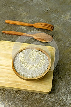 uncooked rice or dry rice. raw rice in wooden bowl with wooden spoon and fork