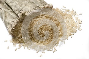 Uncooked rice grains spilled on the table from a burlap sack