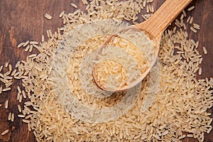 uncooked rice with spoon and woody background