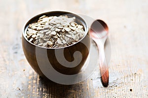 Uncooked rolled oats in wooden bowl