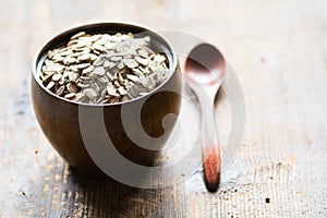 Uncooked rolled oats in wooden bowl