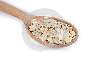 Uncooked rolled oats in wooden spoon, closeup in selective focus