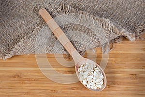 Uncooked rolled oats in wooden spoon on wooden surface