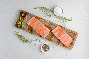 Uncooked salmon fillet on old wooden board. Rosemary, thyme, salt, pepper. Overhead