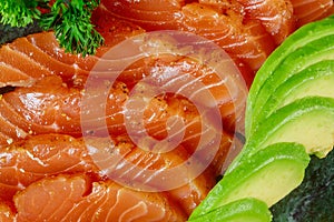 Uncooked salmon fish fillet with avocado, on marble plate, top view ingredients ready to eat