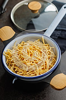Uncooked spaetzle pasta in colander on kitchen table