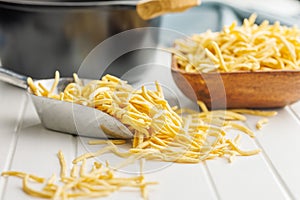 Uncooked spaetzle pasta in scoop on kitchen table