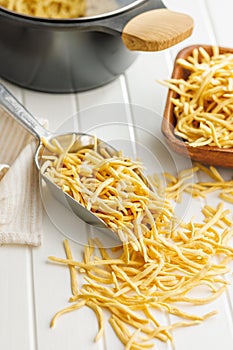 Uncooked spaetzle pasta in scoop on kitchen table