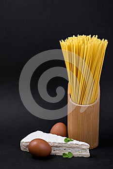 Spaghetti pasta with eggs and cheese on black background, copy space