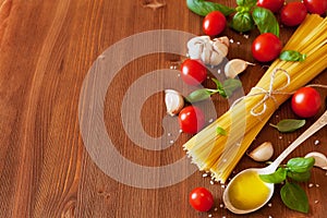 Uncooked spaghetti, cherry tomato, basil, garlic and olive oil, ingredients for cooking pasta, food background