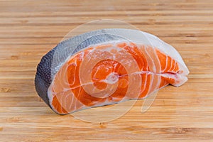 Uncooked steak of arctic char on the wooden cutting board